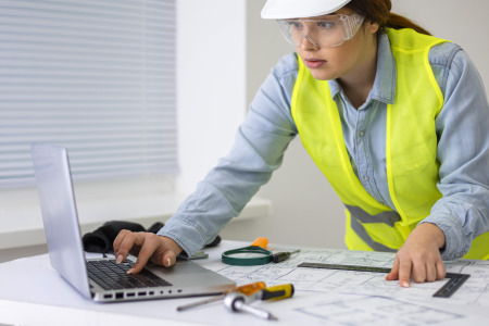 Woman wearing personal protective equipment (PPE) looking at a computer screen during online training